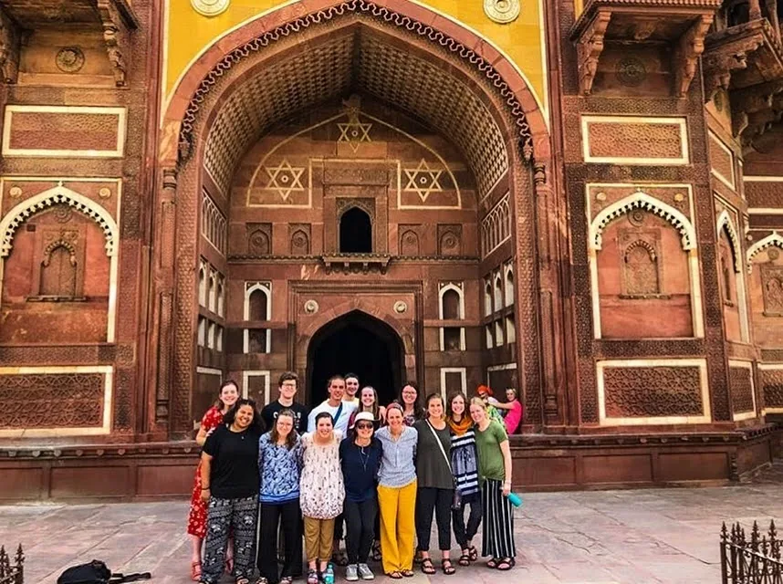 A travelling group gathered under the sandstone arch at Agra Fort